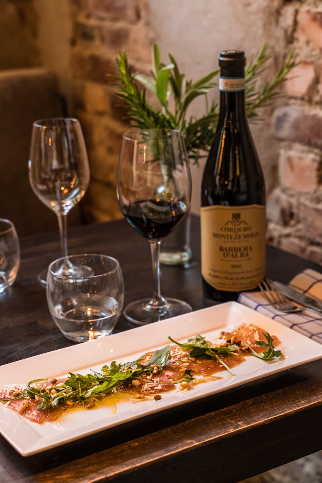 Carpaccio and a glass of red wine against the brick wall